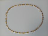 gold and silver beaded necklace on a white surface