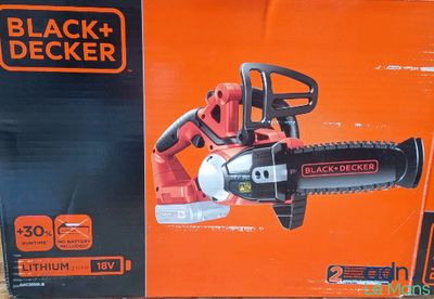 La tronçonneuse électrique Black & Decker se trouve dans la boîte posée par terre.