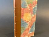 an old book with a brown cover sitting on top of a table