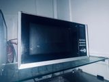 un micro-ondes posé sur une étagère en verre