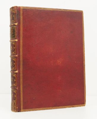 un vieux livre à la couverture rouge posé sur une surface blanche