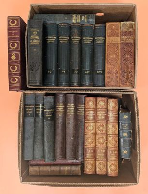 an open cardboard box filled with old books sitting on top of a pink surface