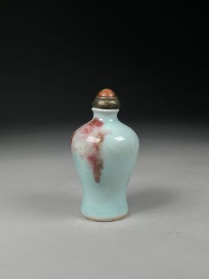 un petit vase bleu avec un couvercle marron posé sur une table