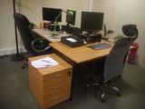 a desk with two computers and a chair in front of it