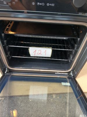 un four noir dont la porte est ouverte et sur laquelle est accrochée une pancarte