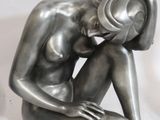 a silver statue of a woman sitting on the ground