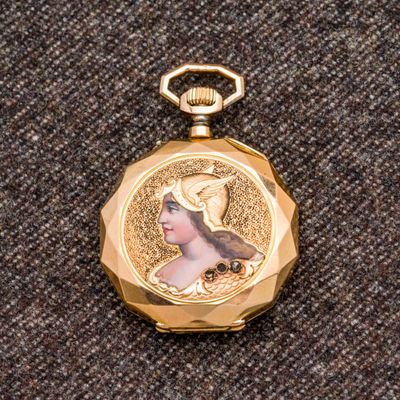 une montre de poche de couleur dorée sur laquelle figure le portrait d'une femme