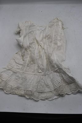 une robe blanche posée sur une surface blanche, avec un fond noir