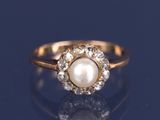 un gros plan d'une bague en perle et diamants posée sur un fond bleu