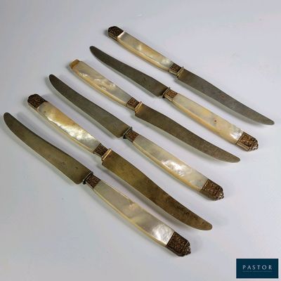 six couteaux sont alignés sur une surface blanche