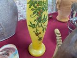 a yellow vase on a table with a lamp on it
