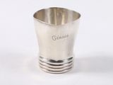 une tasse en argent posée sur une surface blanche