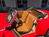 a red car with a tan leather seat in front of a white building
