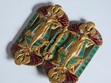 deux broches dorées et vertes sur un fond blanc