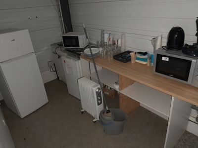 une petite cuisine équipée d'un micro-ondes, d'un réfrigérateur et d'autres ustensiles posés sur le plan de travail