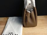 brown coach purse with white cloth and a white bag on a wooden table