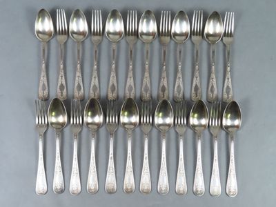 six fourchettes et six cuillères sont disposées en rangée sur une table