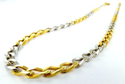 un gros plan d'un collier en or et en argent posé sur une surface blanche