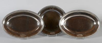 three silver plated dishes on stands on a white surface