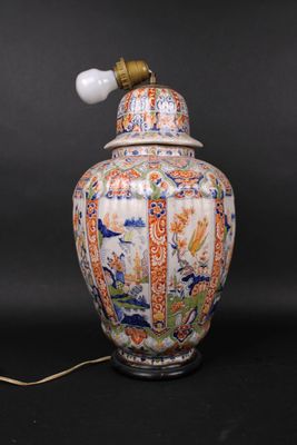 an oriental vase with a lamp on top of it on a black surface