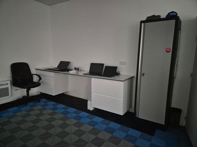 an image of a room with a refrigerator, desk, and computer