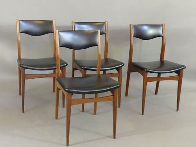 quatre chaises aux sièges en cuir noir sont alignées contre un mur blanc