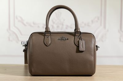 un sac à main Coach posé sur une table, muni d'une étiquette
