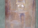 a metal plaque with a vase and a glass on it
