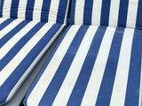 two blue and white striped lounge chairs sitting on the ground