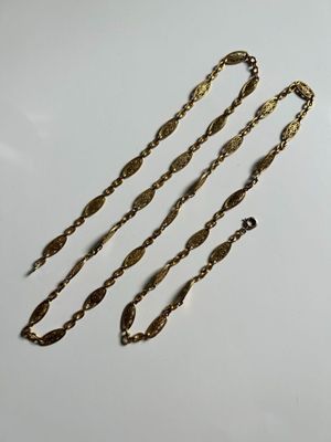 a close up of three gold chains on a white surface