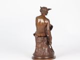 bronze statue of a man sitting on a tree stump holding a bird
