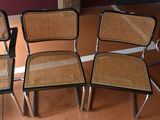 three chairs with wicker seats sit in a room with a red chair