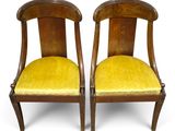 two wooden chairs with yellow upholstered cushions on a white background