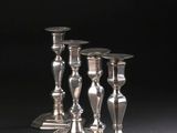 quatre bougeoirs en argent sont alignés sur une surface noire