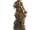 une statue antique en bronze représentant une femme avec un oiseau sur l'épaule