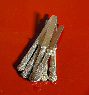 five silverware knives on a red surface