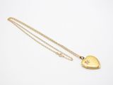 a gold heart shaped locke with a chain on a white background