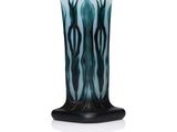 un vase noir et bleu posé sur une table blanche