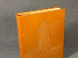 an orange book sitting on top of a table next to a gray wall