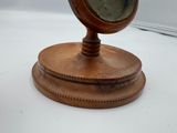 a small wooden clock on a stand on a white surface
