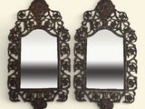 une paire de miroirs richement sculptés accrochés à un mur blanc
