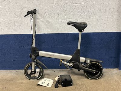 une petite trottinette électrique posée contre un mur bleu et blanc