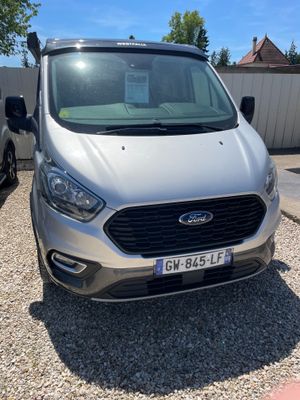 une camionnette argentée garée sur un parking à côté d'autres voitures