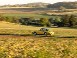 a yellow car that is driving on a dirt road