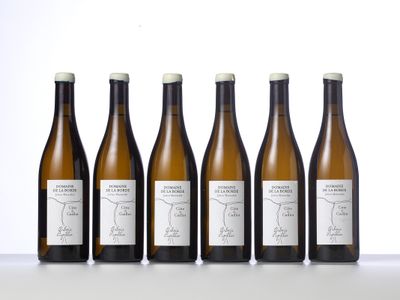 six bouteilles de vin sont alignées sur une table