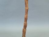 une photo d'une sculpture représentant un bâton en bois posé sur un socle noir