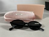 black sunglasses with a pink case sitting on a table next to a pair of glasses