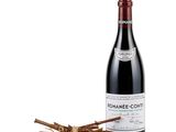 a bottle of red wine next to a bunch of sticks