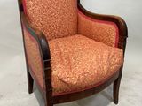 une image représentant une chaise en bois dont l'assise est recouverte d'un tissu rouge et orange