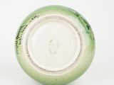 a green and white vase with writing on it
